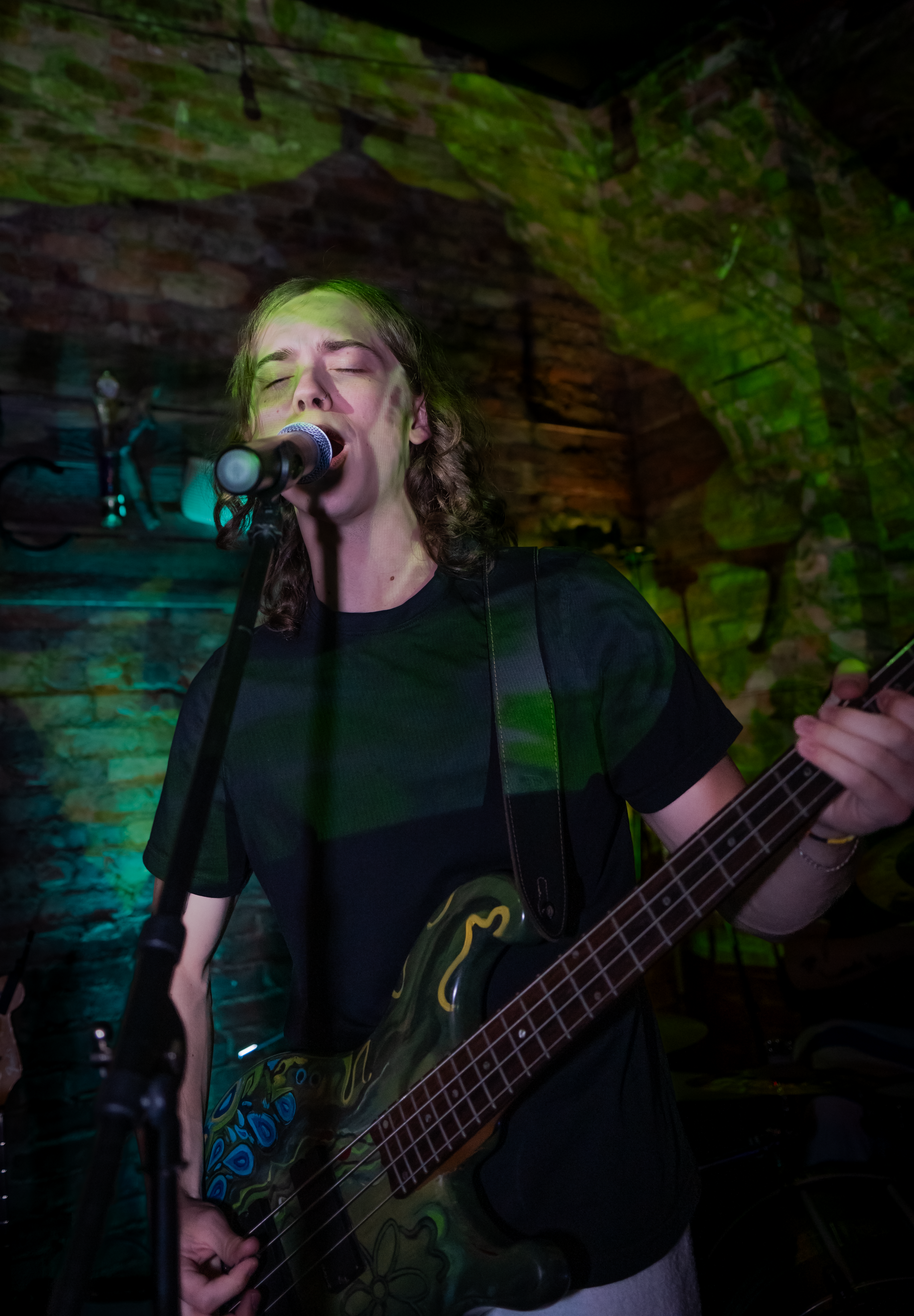 Arlan singing and playing bass guitar at Reason & Ruckus